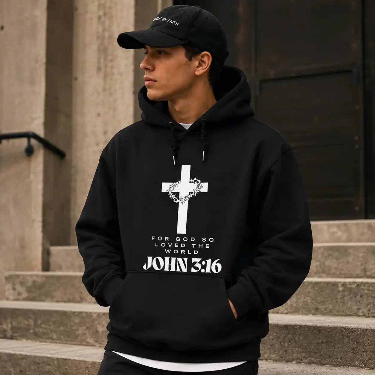 Person wearing a black John 3:16 hoodie with a cross and text design by Soulful Faith, standing on steps.