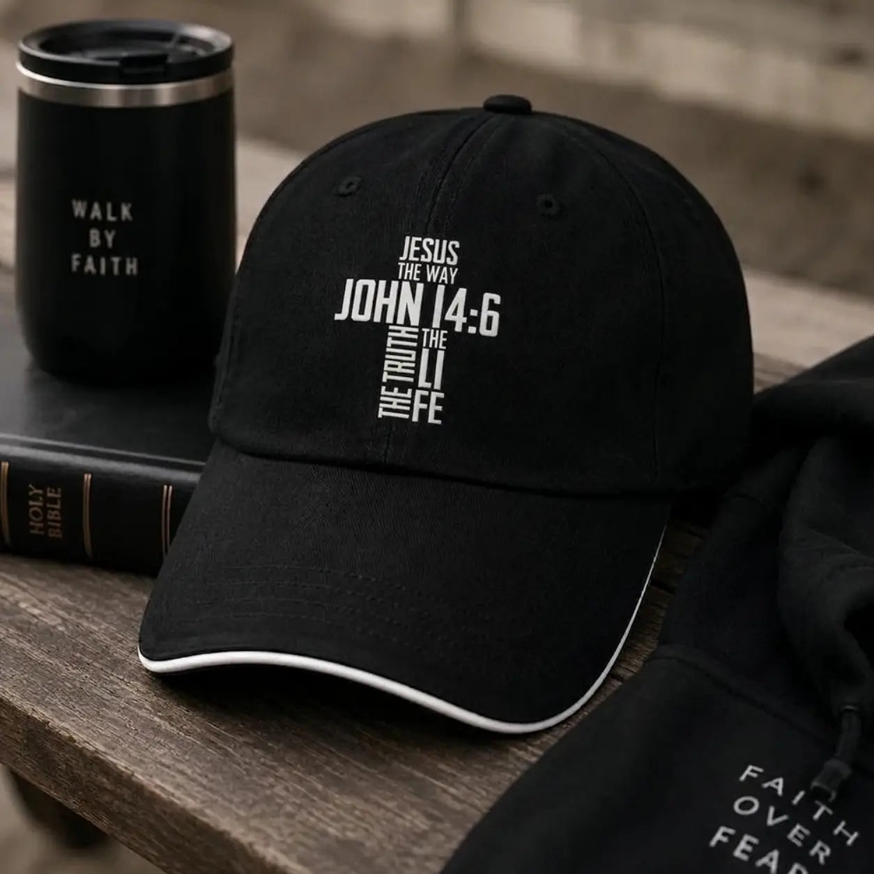 Black John 14:6 cap with religious text by Soulful Faith, black tumbler, and bible on a wooden surface